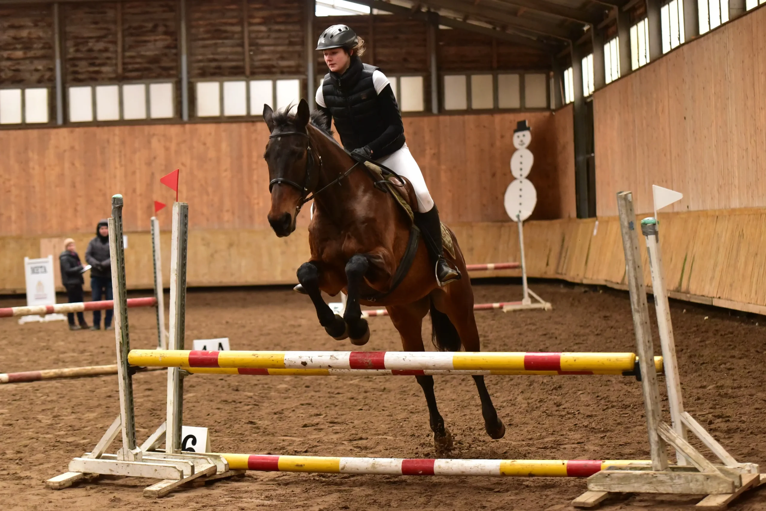 Kobieta skacze na koni na hali jeździeckiej w zimę